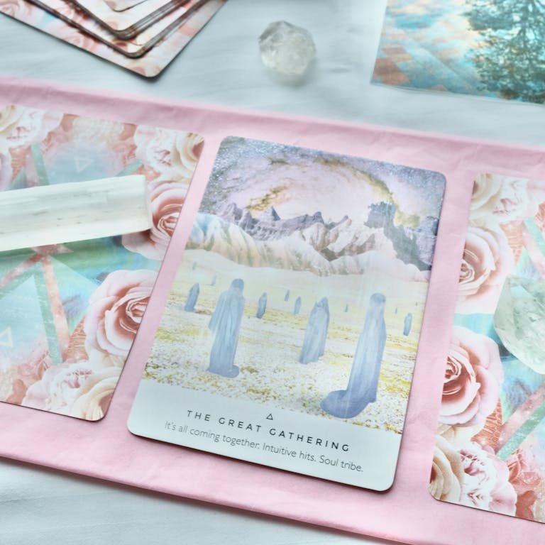 A close-up view of tarot cards and crystals on a pastel background, emphasizing spiritual themes.