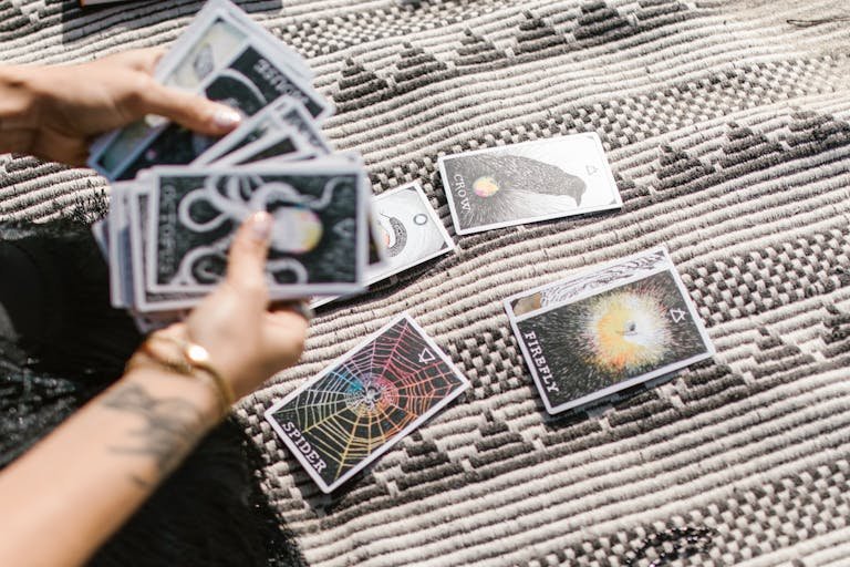 Hands pulling tarot cards for a reading on a stylish geometric rug.